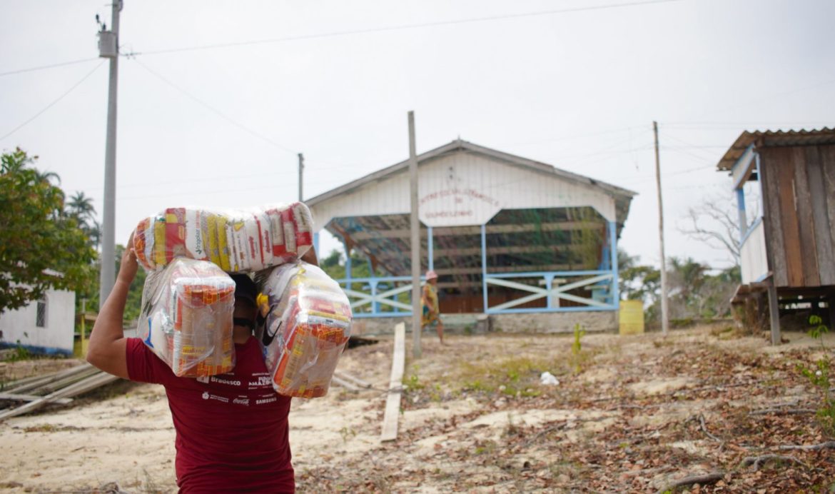 Colaborador da Fundação Amazônia Sustentável (FAS) levando cestas básicas para comunidade indígena localizada no Amazonas.