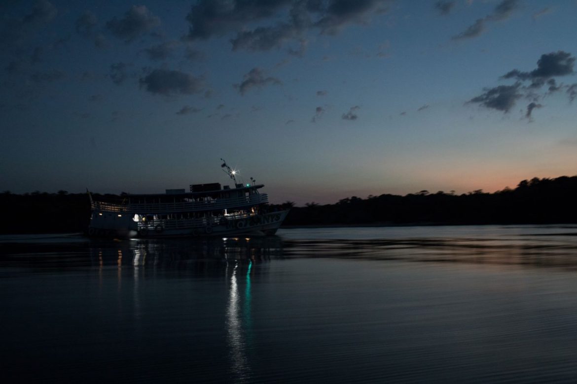 Barco navegando pelo rio ao entardecer no Amazonas.