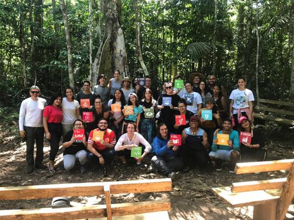 Pessoas reunidas em sala de aula na floresta.