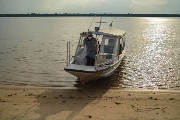 Agente de saúde saindo de lancha segurando equipamentos de saúde.