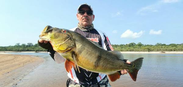 Pescador segurando tucunaré, peixe típico da Amazônia.