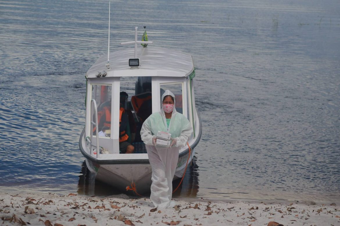 Profissional de saúde chegando com equipamentos em comunidade indígena localizada no Amazonas.
