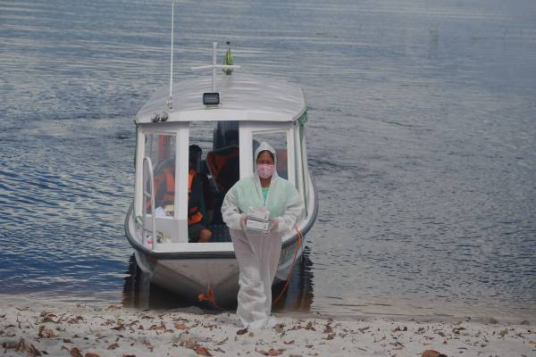 Profissional de saúde chegando com equipamentos em comunidade indígena localizada no Amazonas.