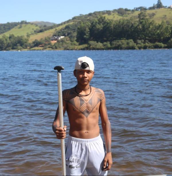 Ribeirinho em pé próximo à beirada do rio, segurando um remo.