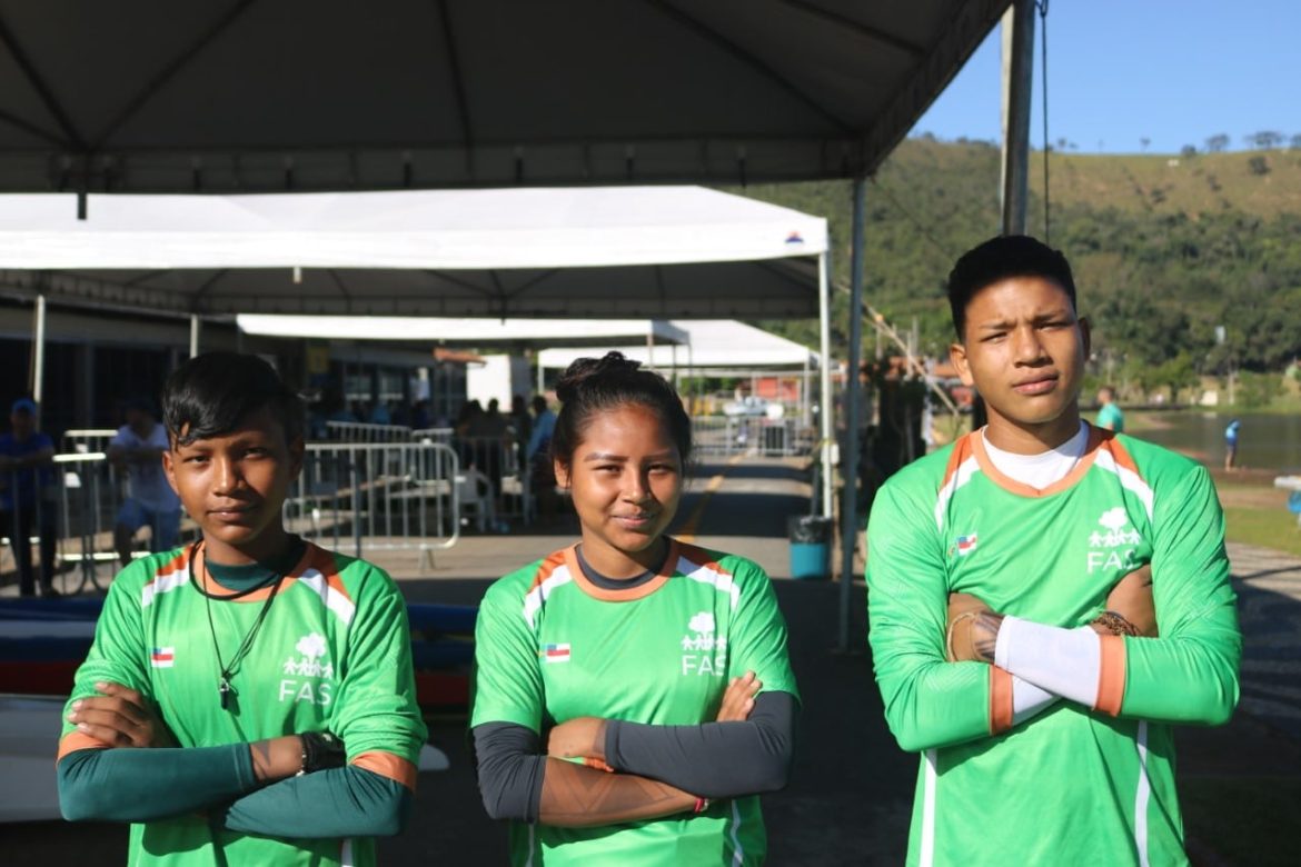 Três jovens indígenas participando de competição nacional de canoagem.