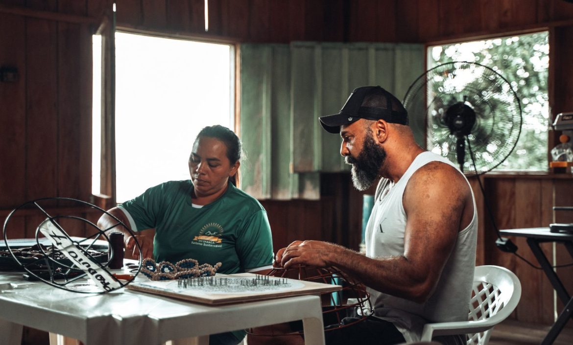 Duas pessoas fazendo artesanato na Comunidade do Sacará, localizada na Amazônia.