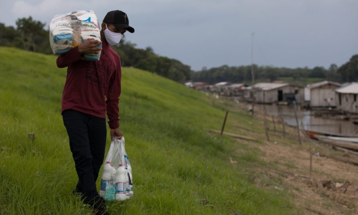 Homem carregando cesta básica que foi doada através da Fundação Amazônia Sustentável (FAS).