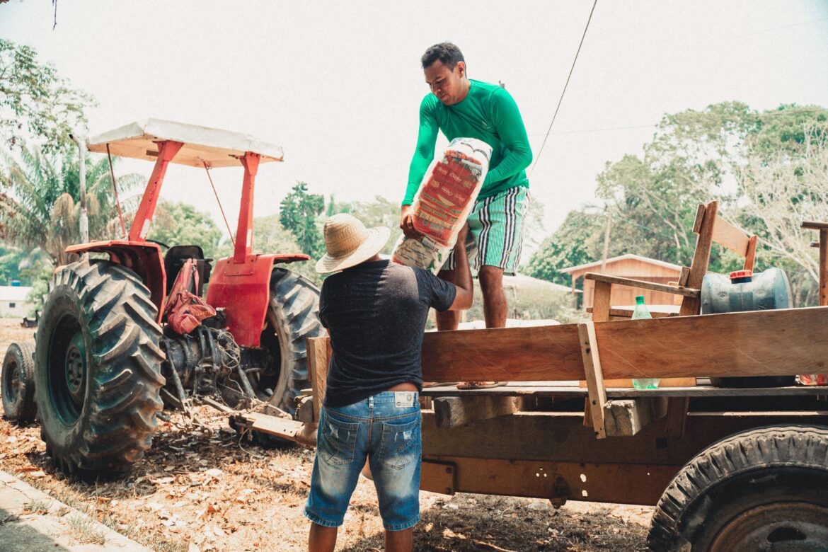 Homens carregando cesta básica durante ação no interior do Amazonas.