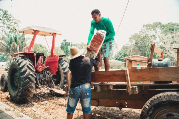 Homens carregando cesta básica durante ação no interior do Amazonas.